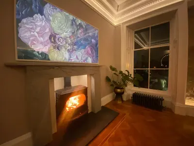 a fireplace in a living room with a painting on the wall at Ashton View in Glasgow