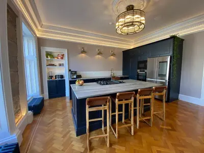 a kitchen with blue cabinets and a large island with bar stools at Ashton View in Glasgow