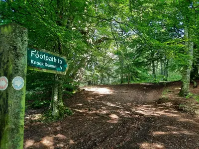 a sign on a dirt road in a forest at Bank Place in Crieff
