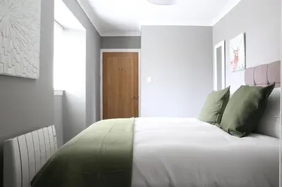 a bedroom with a large white bed with green pillows at Bank Place in Crieff