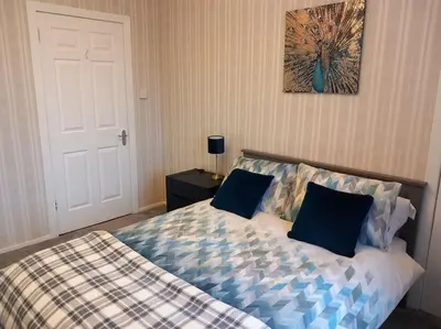 a bedroom with a bed with blue pillows on it at Springfield Apartment - Train to Glasgow or Edinburgh - Private Parking & Wifi in Airdrie