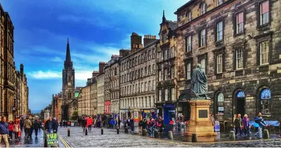 a crowd of people walking down a city street with buildings at Springfield Apartment - Train to Glasgow or Edinburgh - Private Parking & Wifi in Airdrie