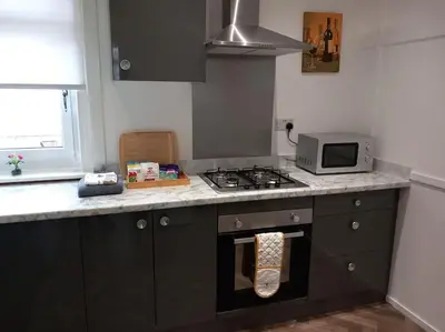 a kitchen with a stove and a microwave at Springfield Apartment - Train to Glasgow or Edinburgh - Private Parking & Wifi in Airdrie