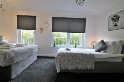 a bedroom with two beds and two windows at Signature - Belvidere House in Glasgow