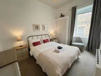 a bedroom with a white bed with red pillows and a window at King’s stable 2 rooms in Edinburgh