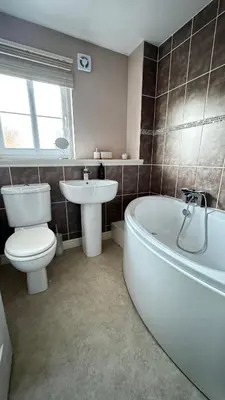 a bathroom with a tub and a toilet and a sink at 6 Tobar Oisinn in Oban
