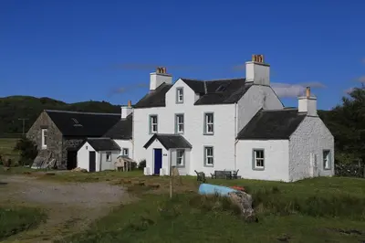 a large white house sitting on top of a field at Old Ferry House in Auchnacraig