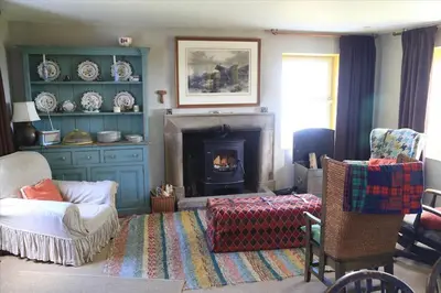 a living room with a fireplace and a couch and chairs at Old Ferry House in Auchnacraig