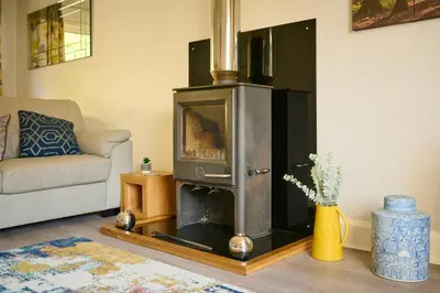 a living room with a wood stove in the corner at Charming 2BD House - Parking & Garden in Oban in Oban