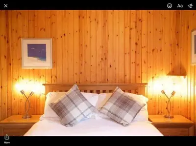 a bedroom with wooden walls and a bed with pillows at The Crannog on Loch Tay in Morenish