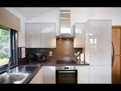 a kitchen with white cabinets and a sink at The Crannog on Loch Tay in Morenish