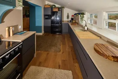 a large kitchen with a counter and a refrigerator at ISLE OF GIGHA FARM HOUSE in Isle of Gigha