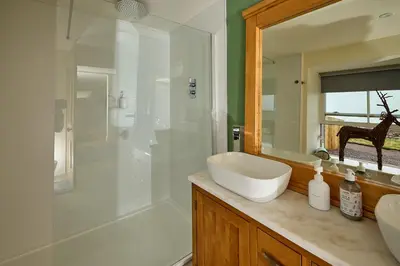 a bathroom with a sink and a shower with a mirror at ISLE OF GIGHA FARM HOUSE in Isle of Gigha