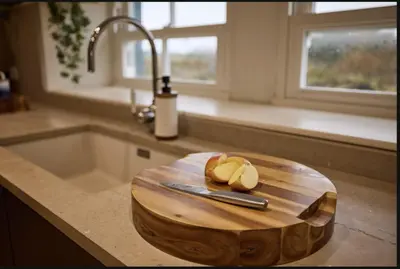 a cutting board on a kitchen counter with a sink at ISLE OF GIGHA FARM HOUSE in Isle of Gigha