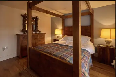 a bedroom with a four poster bed with a wooden frame at ISLE OF GIGHA FARM HOUSE in Isle of Gigha