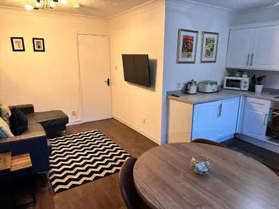 a living room with a table and a kitchen at BrightCentral Apartment With Parking in Glasgow