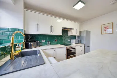 a kitchen with white cabinets and a sink at New Slick Finnieston Pad w/ Free Parking in Glasgow