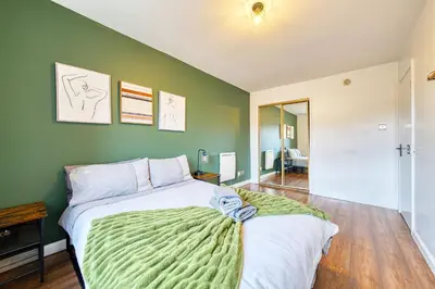 a bedroom with a large bed with a green wall at New Slick Finnieston Pad w/ Free Parking in Glasgow