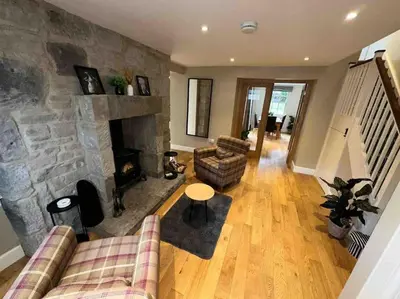 a living room with a couch and a stone fireplace at The Gate House - 3 Bed & Parking in Edinburgh