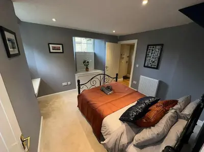 a bedroom with a bed with an orange blanket at The Gate House - 3 Bed & Parking in Edinburgh
