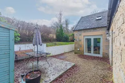 a patio with a table and a bench and an umbrella at The Gate House - 3 Bed & Parking in Edinburgh