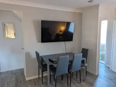 a dining room with a black table and chairs at Lovely 2 Bedroom Terrace House in Coatbridge