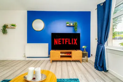 a living room with a tv and a blue wall at Sleek and Stylish 3 Bed in Greenock - Sleeps 8 in Greenock