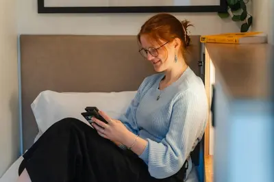 a woman sitting on a bed looking at her cell phone at CODE - The Loft, Edinburgh in Edinburgh