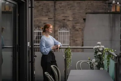 a woman standing on a balcony looking out of a window at CODE - The Loft, Edinburgh in Edinburgh