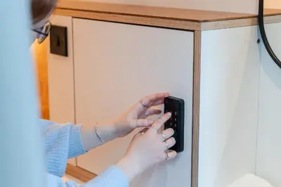 a woman holding a remote control in front of a cabinet at CODE - The Loft, Edinburgh in Edinburgh