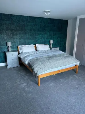 a bedroom with a bed with a green wall at Fairness Cottage, Near Comrie in Comrie