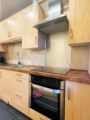 a kitchen with wooden cabinets and a black oven at E'holidays in Edinburgh