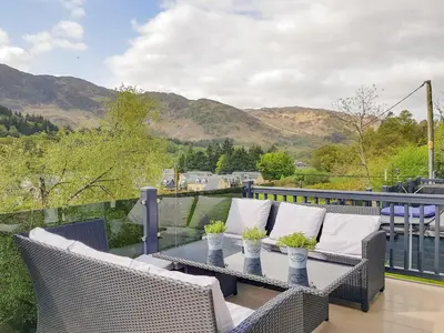 a patio with wicker chairs and a table on a balcony at Ben Vorlich Lodge in Saint Fillans