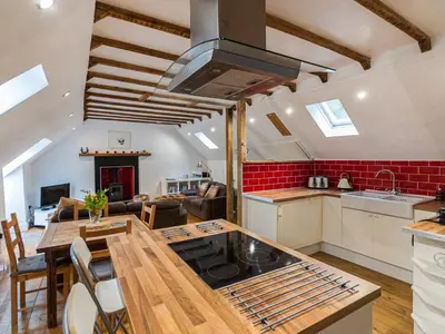a kitchen and living room with a table and a stove at Craigdarroch Cottage in Saint Fillans