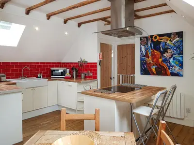 a kitchen with white cabinets and a table with a sink at Craigdarroch Cottage in Saint Fillans