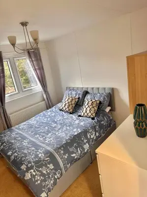 a bedroom with a bed with blue sheets and pillows at Semi-detached 1-Bedroom Chalet at Maryville Caravan Site - Uddingston, Glasgow in Uddingston