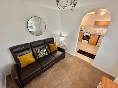 a black leather couch in a living room with a mirror at Semi-detached 1-Bedroom Chalet at Maryville Caravan Site - Uddingston, Glasgow in Uddingston