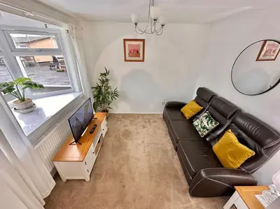 a living room with a black leather couch and a tv at Semi-detached 1-Bedroom Chalet at Maryville Caravan Site - Uddingston, Glasgow in Uddingston