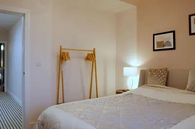 a bedroom with a large bed and a lamp at Stunning Coach House in Largs