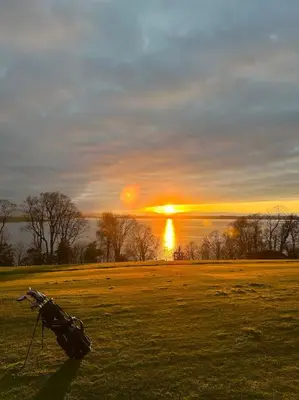 a field with the sun setting in the background at Stunning Coach House in Largs