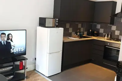 a kitchen with a white refrigerator and a tv at Stunning Ground Floor flat in Southside. in Glasgow