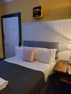 a bedroom with a bed with white pillows and a table at Luxe rooms in Edinburgh
