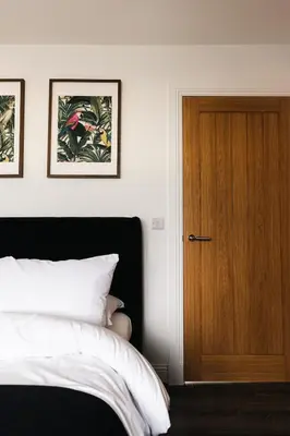 a bedroom with a bed and a wooden door at Barnet House Serviced Apartments in Dunfermline