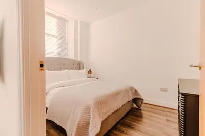a white bedroom with a bed and a window at Barnet House Serviced Apartments in Dunfermline