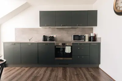 a kitchen with dark green cabinets and appliances at Barnet House Serviced Apartments in Dunfermline