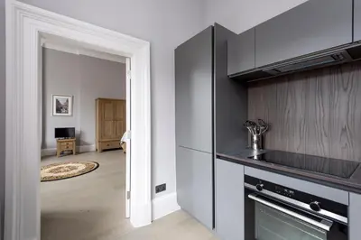 a kitchen with a stove top oven next to a living room at Modern George Street Studio sleeping 2 in Edinburgh