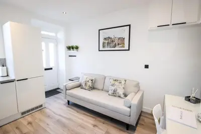a white living room with a couch and a kitchen at City Centre Hub Stirling, On Street Parking. in Stirling