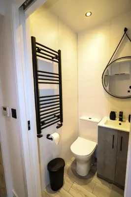a bathroom with a toilet and a sink and a mirror at City Centre Hub Stirling, On Street Parking. in Stirling