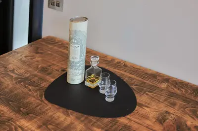 a bottle of whiskey and two glasses on a table at Campbell Street Apartments in Oban