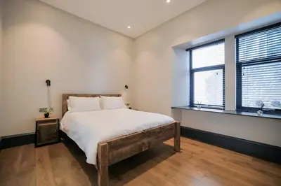 a bedroom with a large bed and two windows at Campbell Street Apartments in Oban